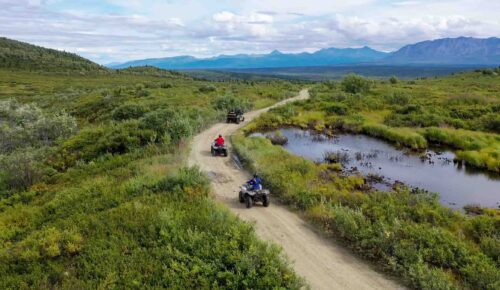 Riders enjoying a scenic ATV tour in Alaska with stunning mountain views