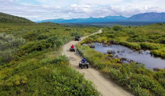 Riders enjoying a scenic ATV tour in Alaska with stunning mountain views