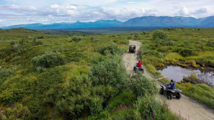 Exploring Alaska on an ATV with towering mountains in the background