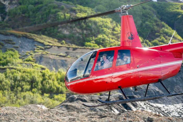 Family in a helicopter taking off from a glacier, enjoying an unforgettable Alaskan tour.