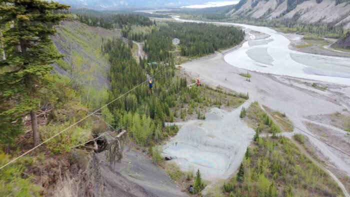 Two riders racing side by side on a zipline, capturing the spirit of adventure in Alaska